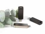 Drei moderne USB-Sticks in elegantem Design, umgeben von Eukalyptusblättern, ideal für individuelle Markenpräsentationen.