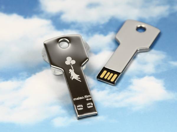 USB-Stick in Schlüssel-Form mit einem spielerischen Motiv einer schwebenden Figur und Platz für individuelle Bedruckung.
