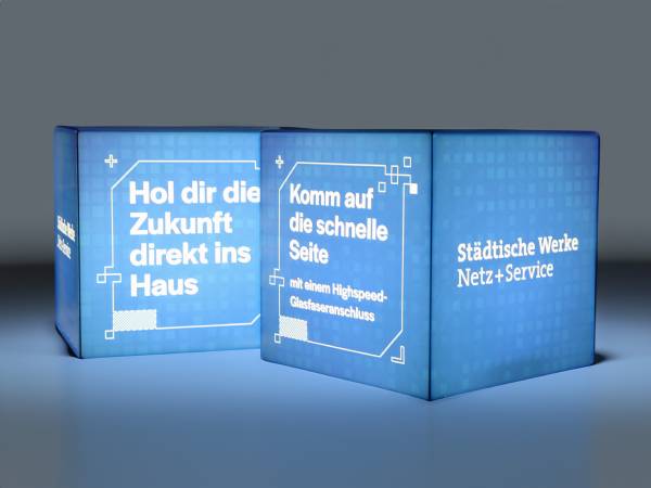 Leuchtender Sitzwürfel mit Werbebotschaften zu Highspeed-Glasfaseranschlüssen und digitaler Zukunft.