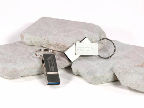 USB-Sticks in modernem Design mit Platz für individuelle Logo-Gestaltung, präsentiert auf grauen Steinplatten.