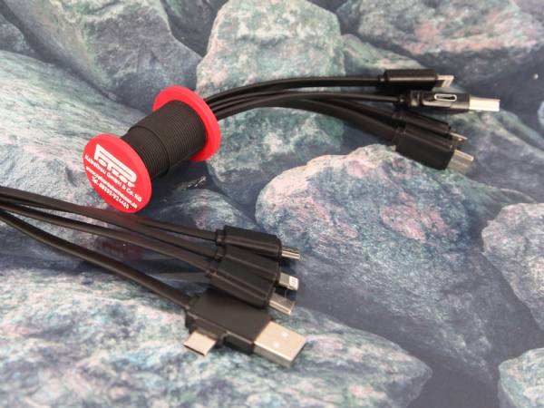 Ladekabel mit mehreren Anschlüssen, stehend auf einer Unterlage, mit individuellem Logo-Bereich in Rot und Schwarz.
