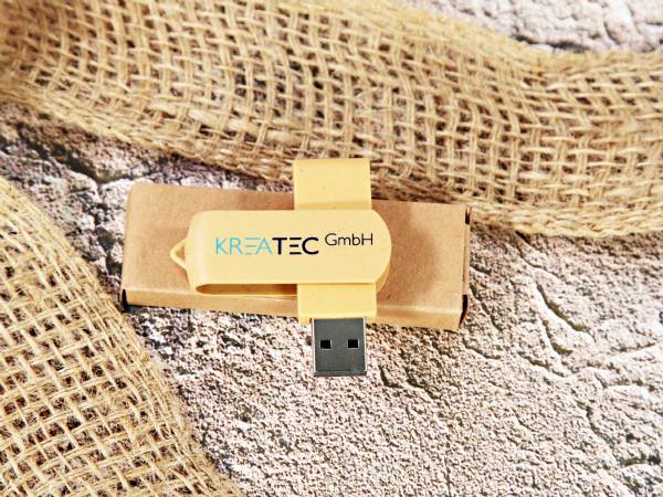 USB-Stick mit gelbem Gehäuse und bedruckbarem Bereich für individuelles Branding, präsentiert auf natürlichem Hintergrund.