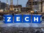 Leuchtende Werbewürfel mit dem Logo der Zech Group auf einer Baustelle, umgeben von Baukränen und Bauarbeiten.