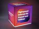 Leuchtender Sitzwürfel mit Werbebotschaft für Highspeed-Internet in Kassel und Vellmar. Modernes Design in lila und orange.