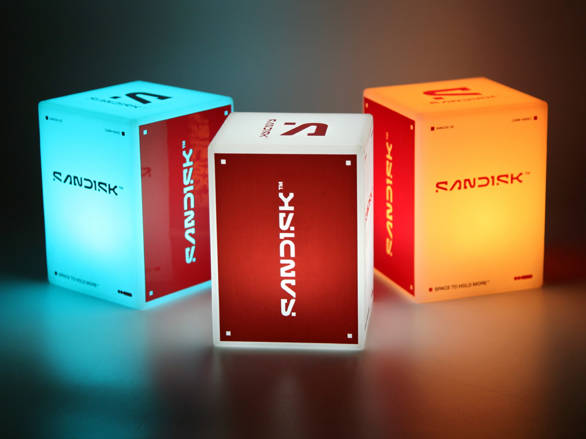 Leuchtende LED-Tischleuchten in cube-Form mit verschiedenen Farben und dem Logo von Sandisk. Ideal für Werbung und Events.
