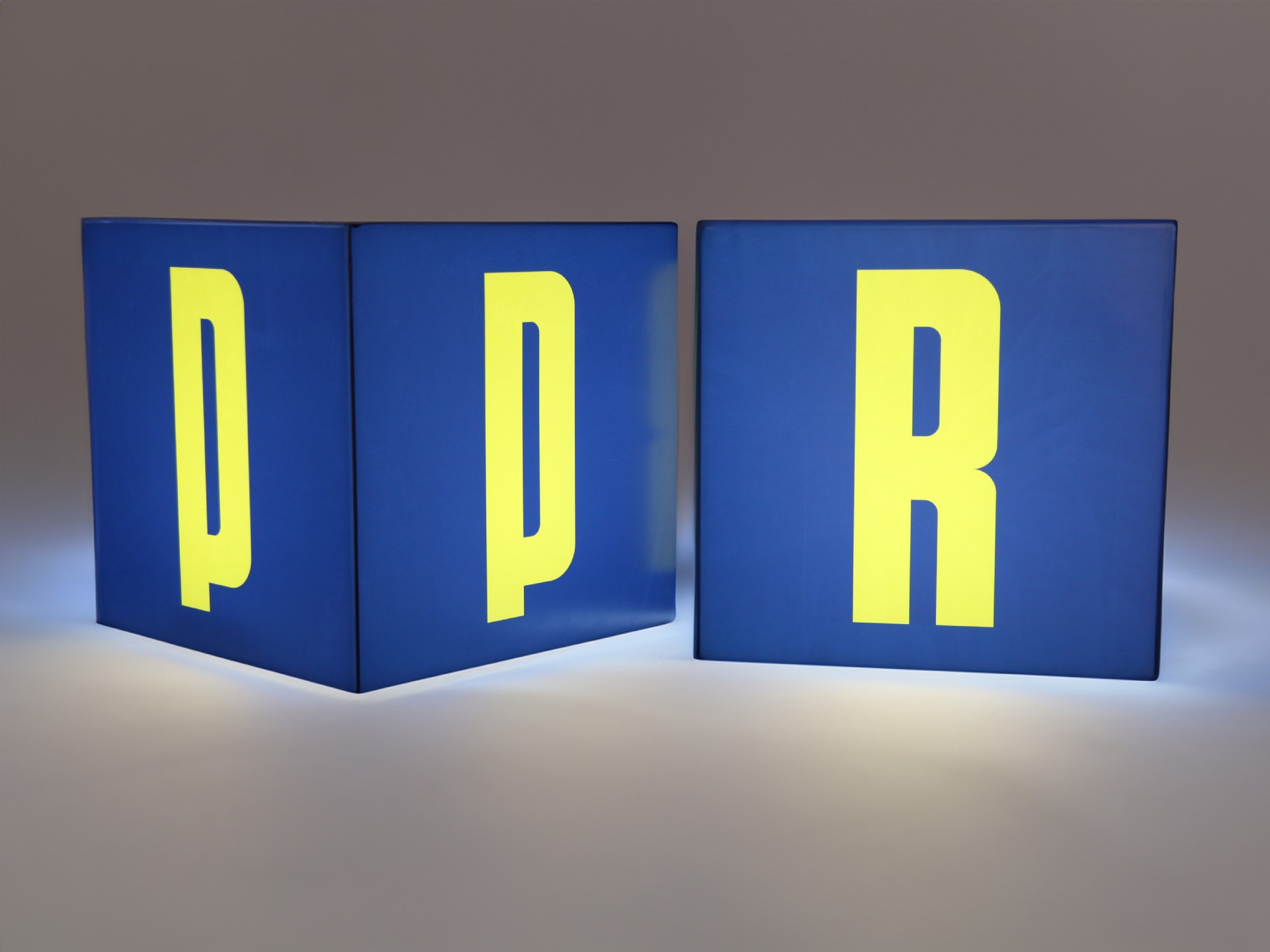 Leuchtwürfel mit blauem Hintergrund und großen gelben Buchstaben, ideal für dekorative Beschriftungen und Werbung.