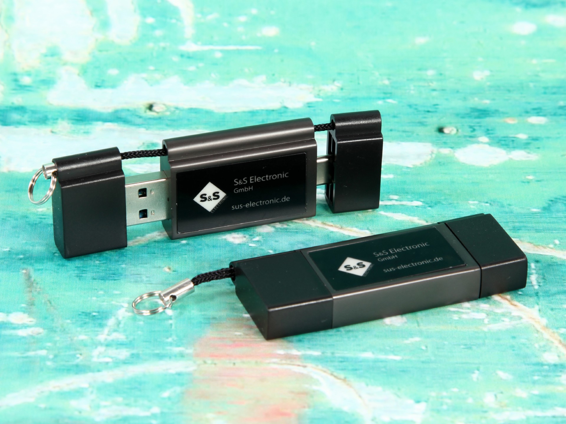 USB-Stick mit schwarzem Gehäuse, individuell bedruckbar und mit zusätzlichem Platz für einen Schlüsselanhänger.