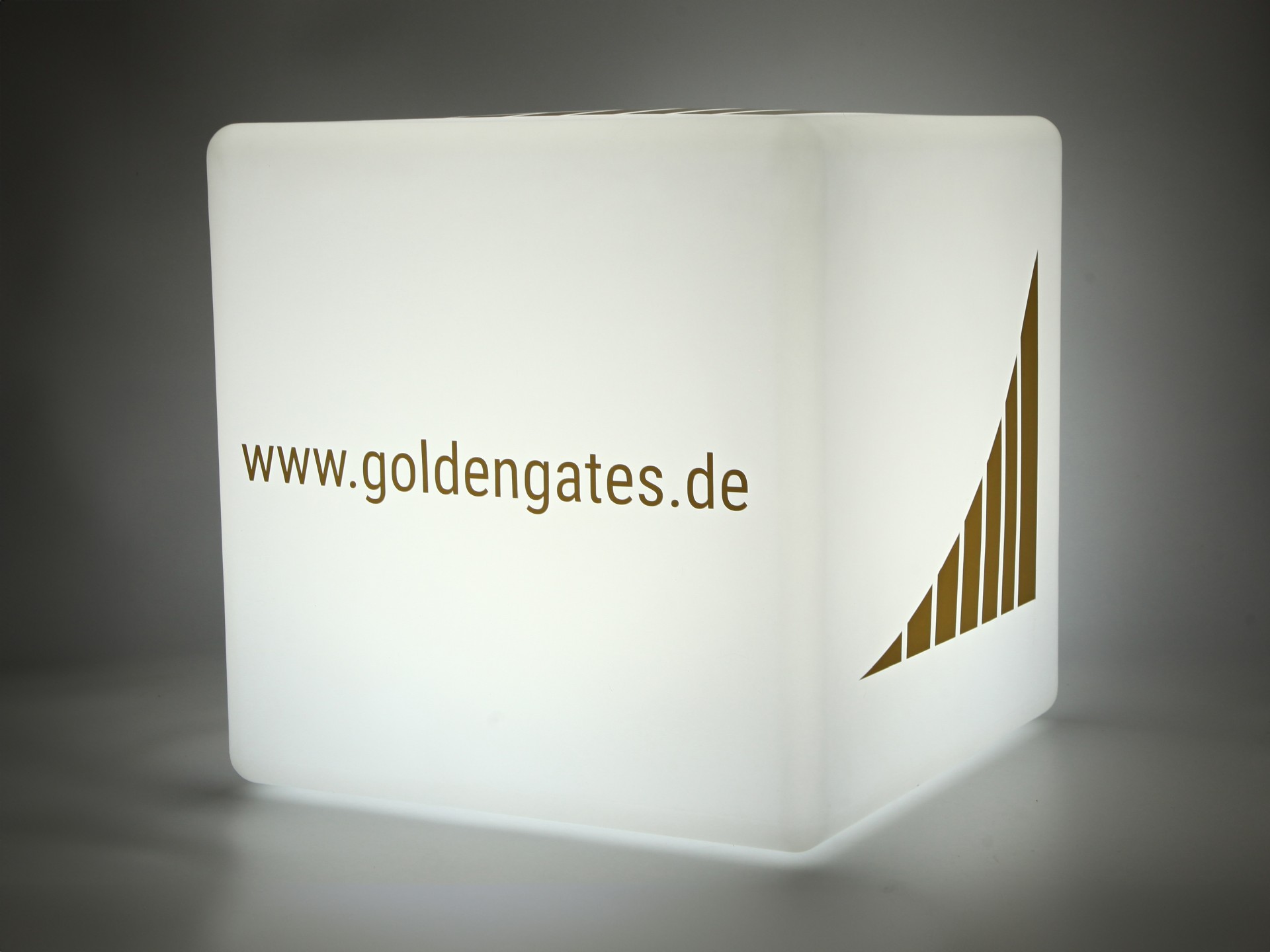 Leuchtender Werbungwürfel mit weißem Gehäuse und goldfarbener Beschriftung für www.goldengates.de.